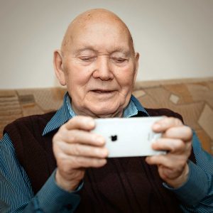 Senior man at home concentrates on using an iPhone